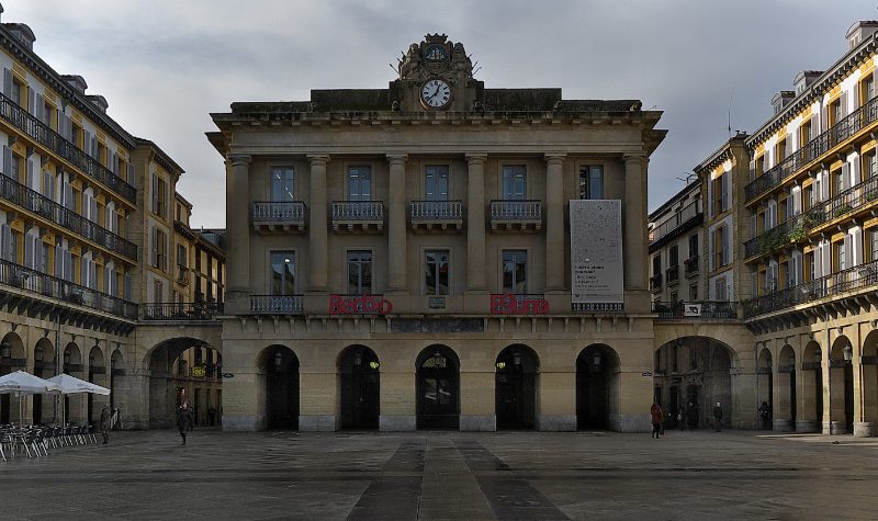 Plaza de la Constitución in San Sebastián's old town: the former town hall with its clock, framed by arcades and balconied façades.